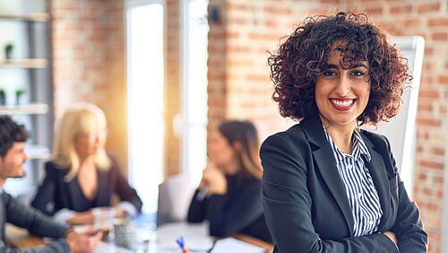 A woman with dark curls smiles into the camera