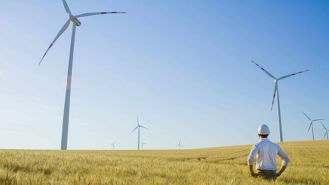 Man standing in front of wind turbine in the field
