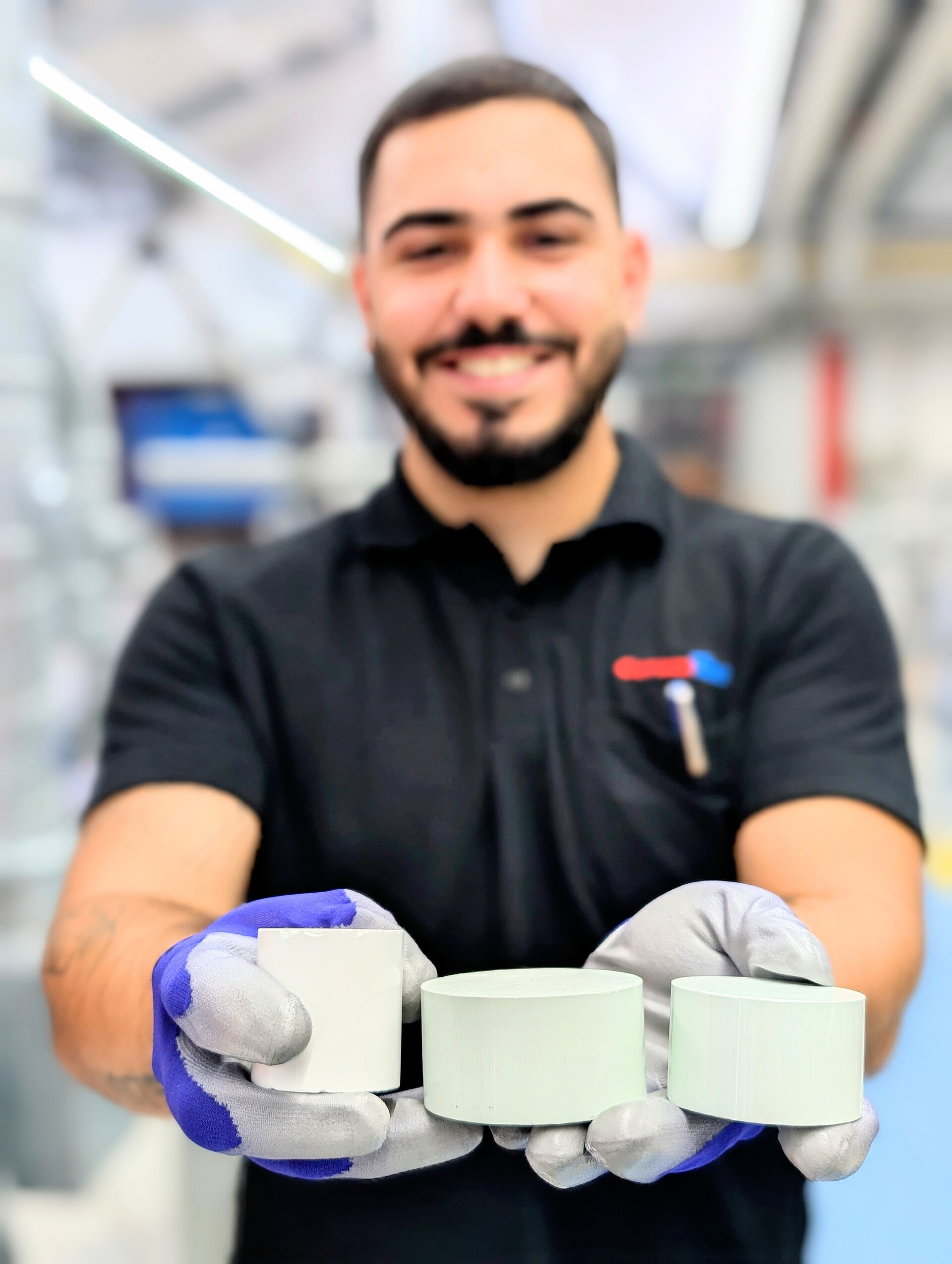 A CeramTec employee from production holds three ceramic blanks in his hands