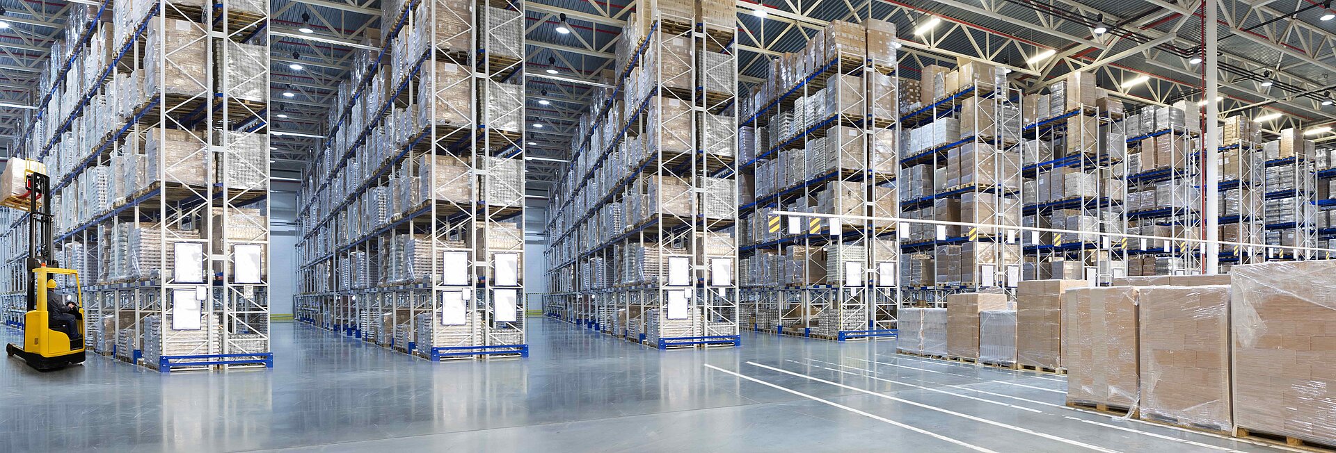 Huge distribution warehouse with high shelves and forklift